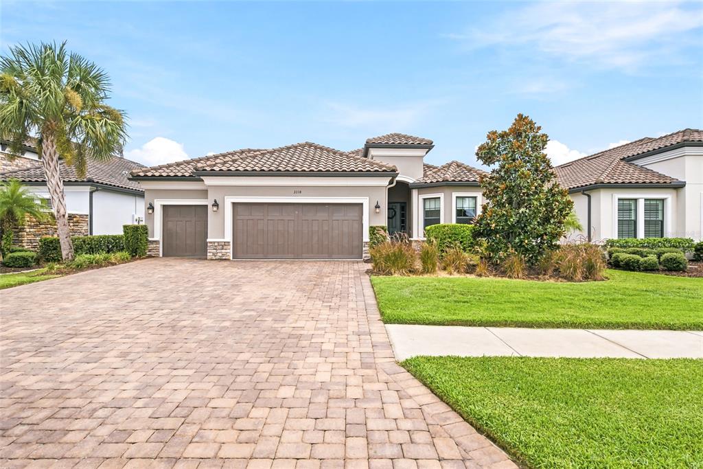 A single-story house with a tiled roof, paver driveway, and a three-car garage — 3118 FORSYTHIA DRIVE, ODESSA, FL