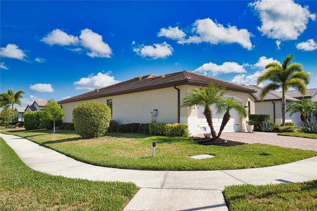 A single-story house with a tiled roof, a paved driveway, and palm trees in Florida — 12064 BLAZING STAR DRIVE, VENICE, FL