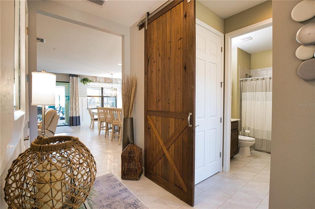 A hallway features a wooden barn door, a decorative lantern, and a view into a bathroom — 12064 BLAZING STAR DRIVE, VENICE, FL
