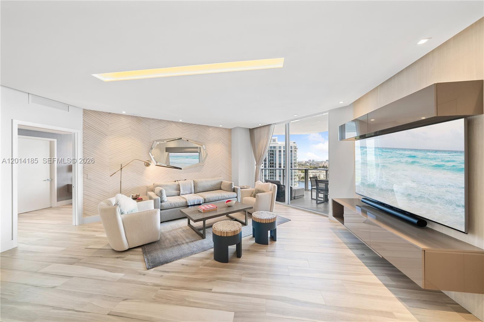 A modern living room features light wood flooring, a large television, and a balcony view — 17111 Biscayne Blvd # 2107, North Miami Beach FL 33160, NORTH MIAMI BEACH, FL