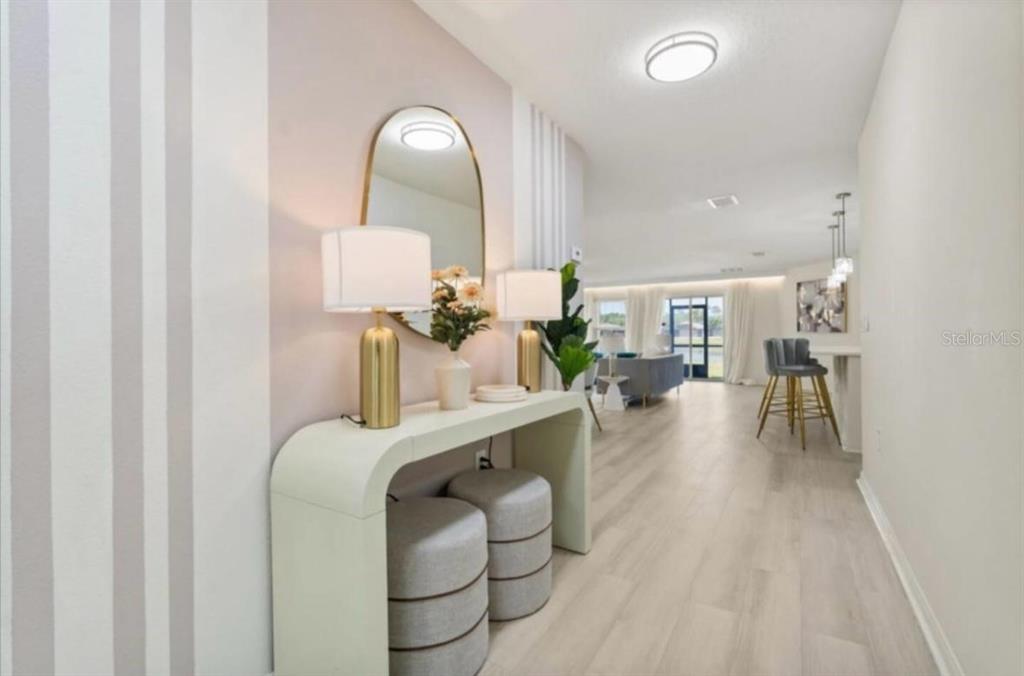 A modern entryway features a console table, two ottomans, and a mirror against striped walls — 4717 BLUE DIAMOND STREET, KISSIMMEE, FL