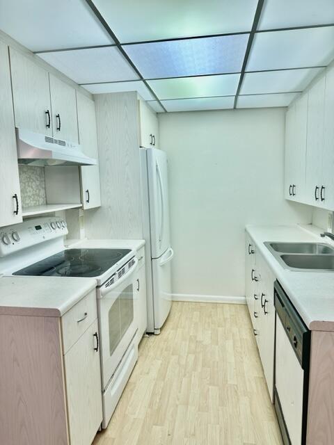 A galley kitchen features light wood-grain cabinets, white appliances, and a drop ceiling with panels — 3063 Ainslie D, Boca Raton FL 33434, BOCA RATON, FL