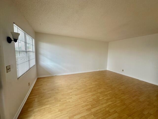 An empty room features light wood-look flooring, white walls, and a window with blinds — 3063 Ainslie D, Boca Raton FL 33434, BOCA RATON, FL