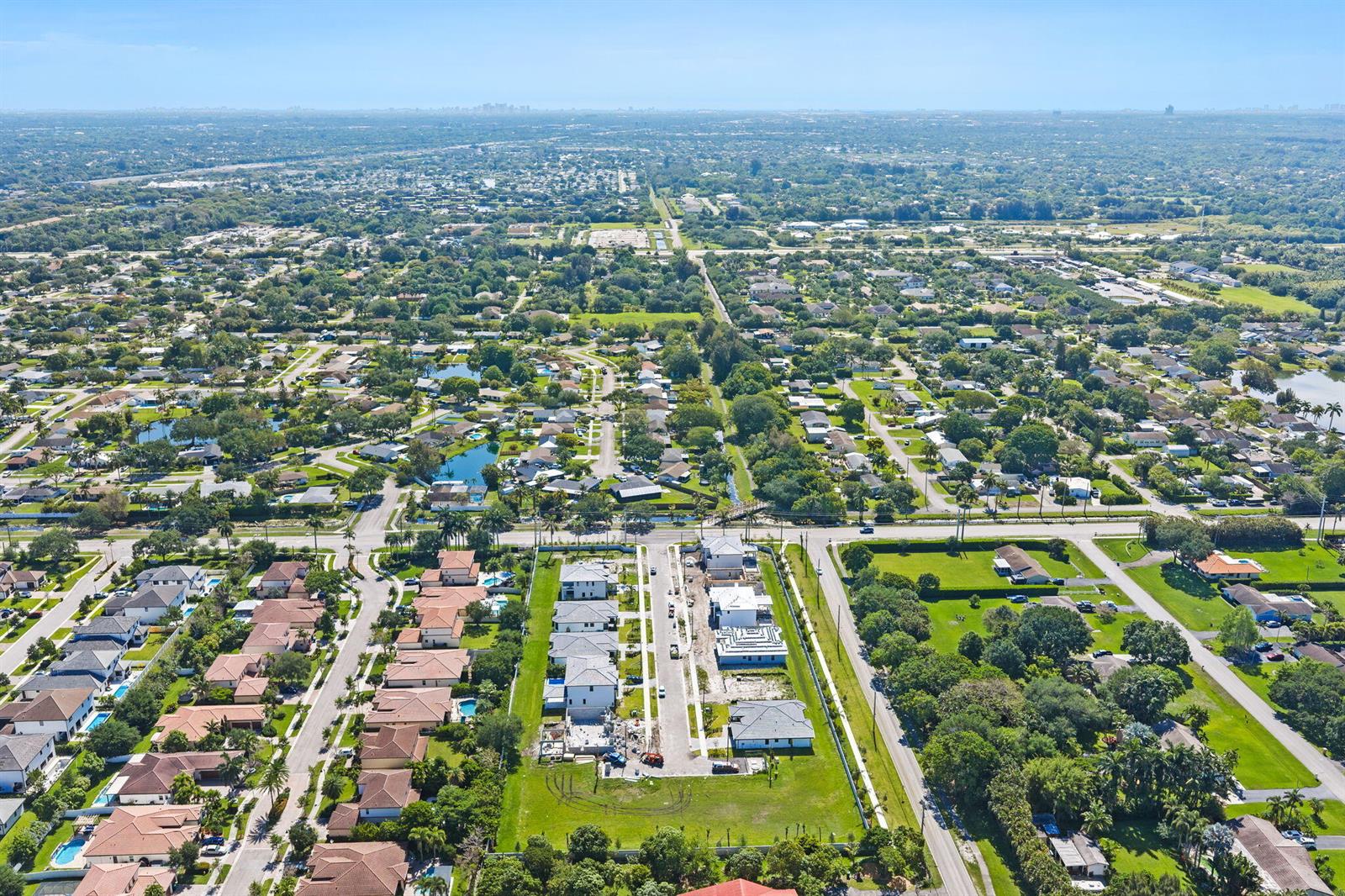 An aerial view shows a suburban neighborhood with houses, green lawns, and a new construction site — 13044 Davie Oaks Drive, Davie FL 33325, DAVIE, FL