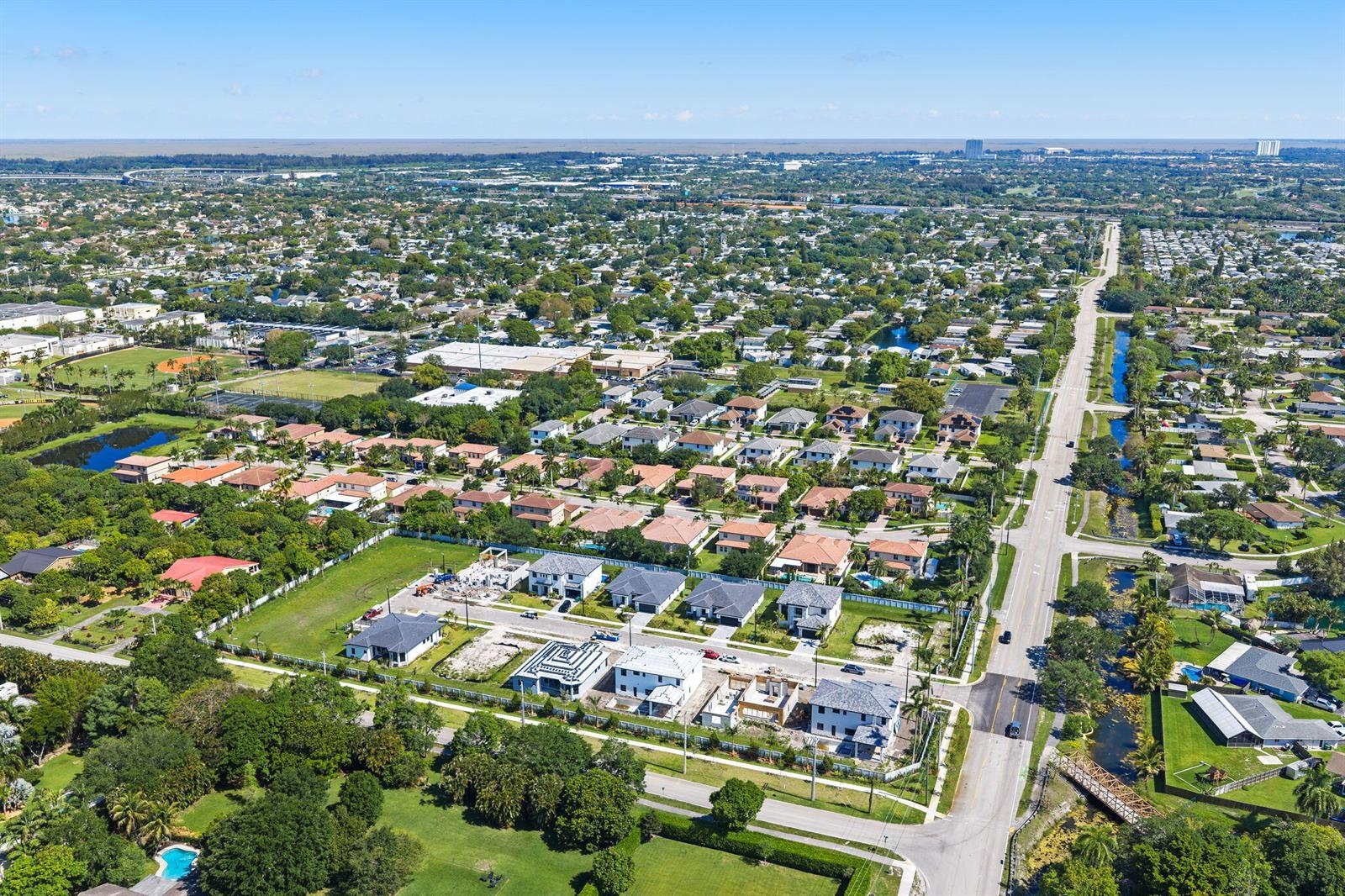 An aerial view shows a suburban neighborhood with new construction homes and a nearby canal — 13044 Davie Oaks Drive, Davie FL 33325, DAVIE, FL