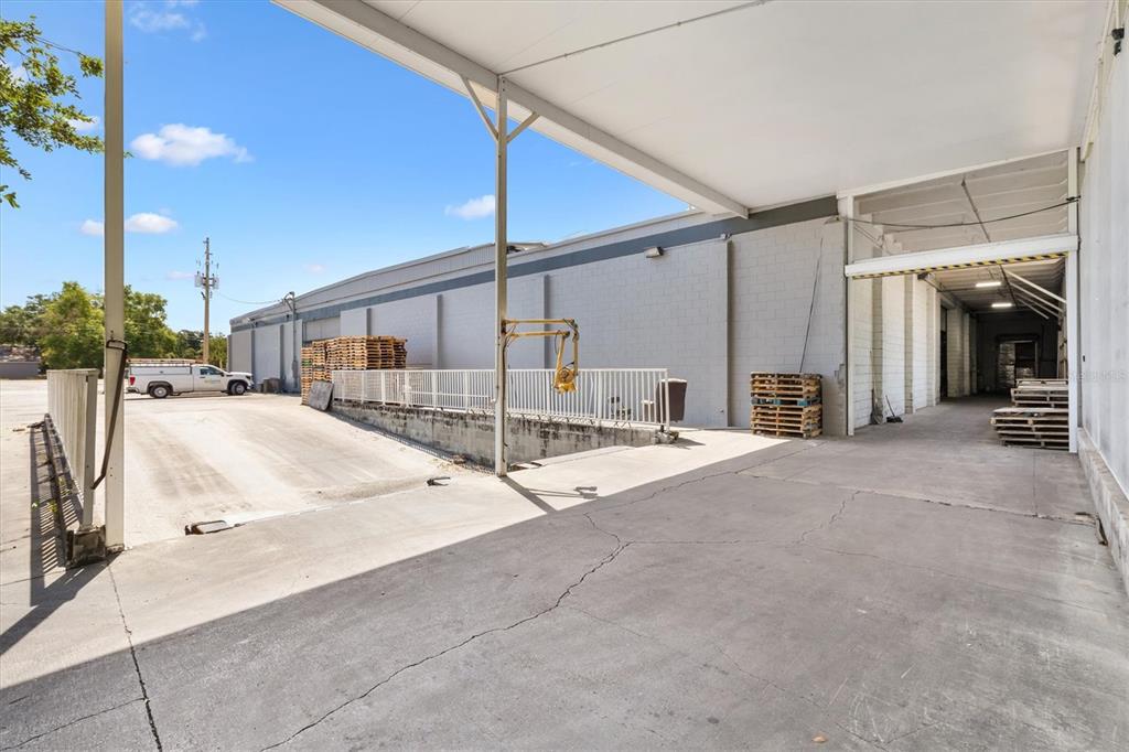 An outdoor loading dock area with a concrete ramp, metal railing, and stacked wooden pallets — 1103 THOMAS AVENUE, LEESBURG, FL