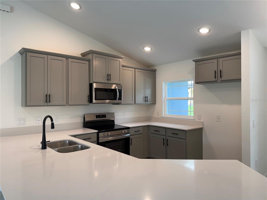 A kitchen features gray cabinets, stainless steel appliances, and white countertops — 4081 BIRNAM TERRACE, NORTH PORT, FL