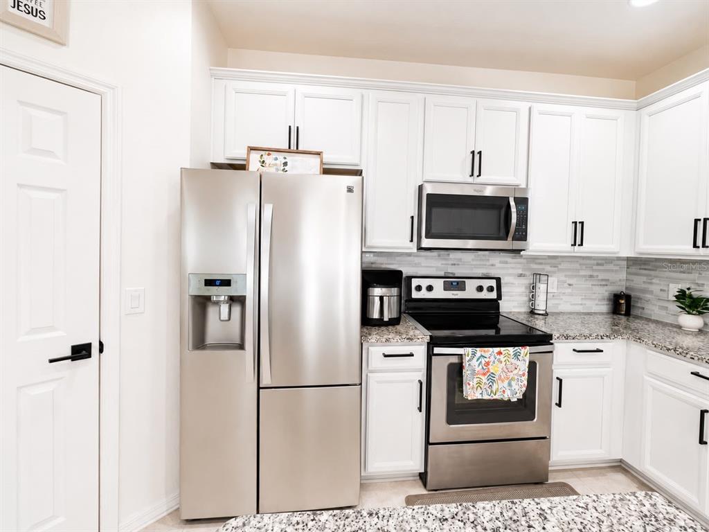 A kitchen features white cabinets, stainless steel appliances, and granite countertops — 3517 VEGA CREEK DRIVE, ST CLOUD, FL