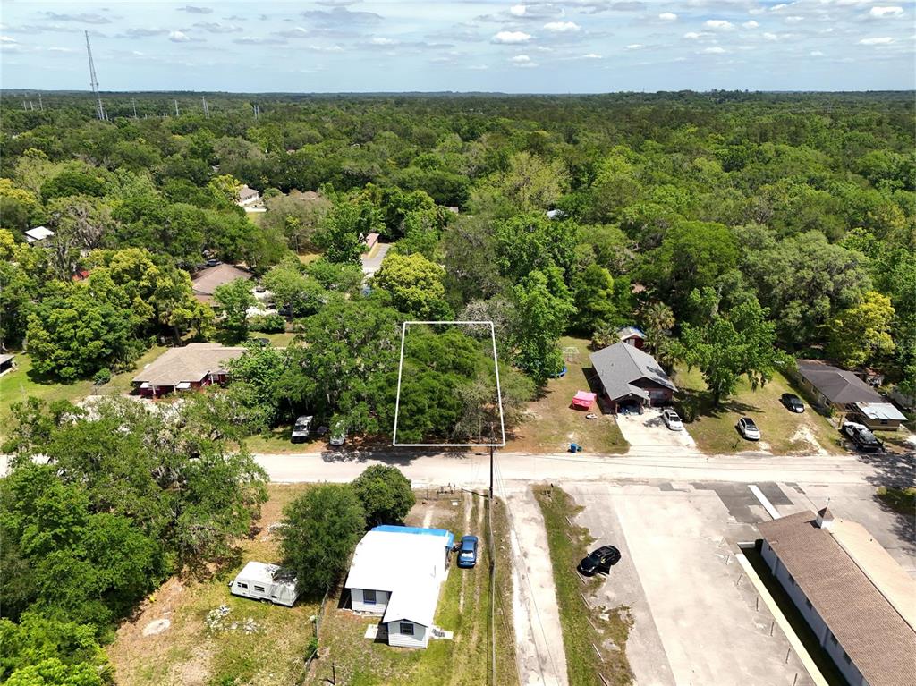 An aerial view shows a vacant, tree-covered lot outlined in white between two houses — JOSEPHINE STREET, BROOKSVILLE, FL