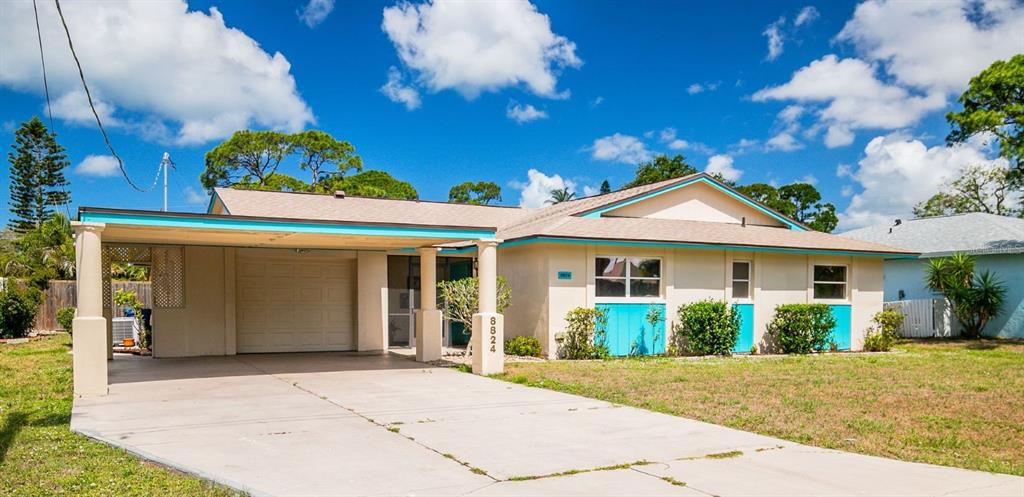 A single-story house with a carport, light-colored stucco walls, and bright blue trim — 8824 PHYLISS AVENUE, SARASOTA, FL