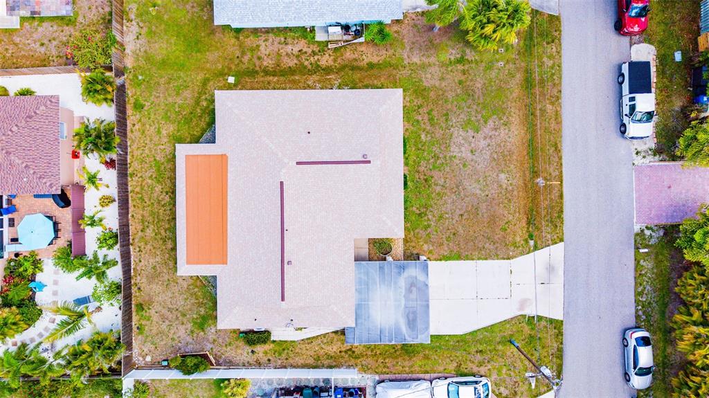 An aerial view shows a house with a light-colored roof, a driveway, and surrounding yard — 8824 PHYLISS AVENUE, SARASOTA, FL