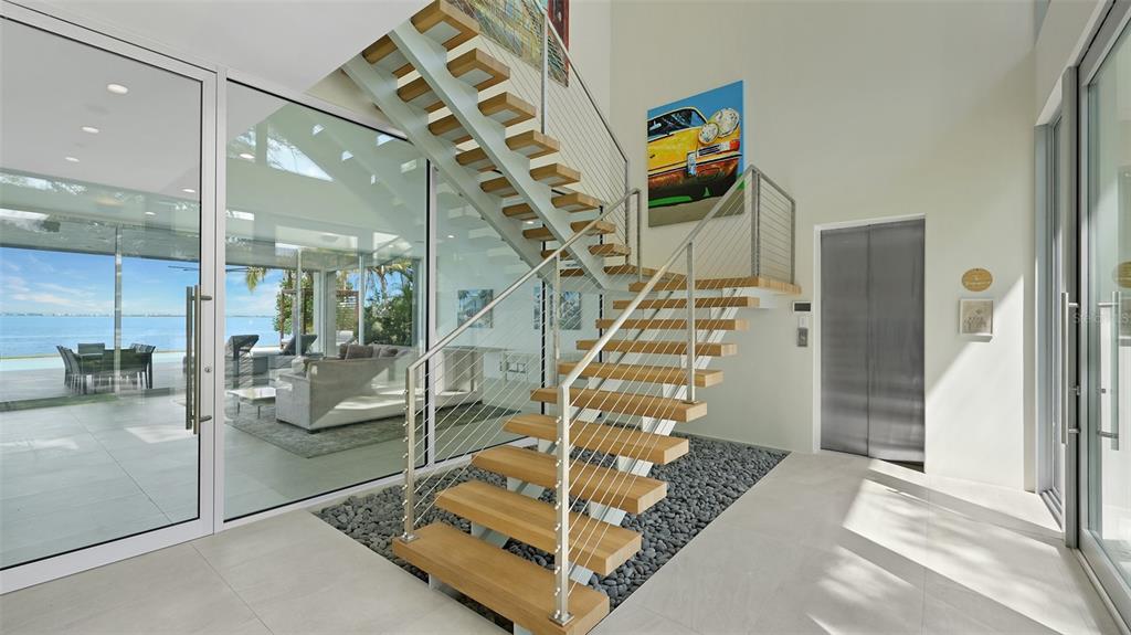 A modern two-story house with a large infinity pool and expansive glass walls at dusk — 4123 BAY SHORE ROAD, SARASOTA, FL