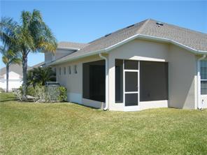 A beige house exterior features a screened-in porch and a palm tree on the lawn — 434 N Tangerine Square SW, Vero Beach FL 32968, VERO BEACH, FL