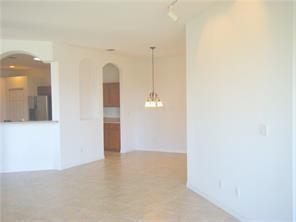 An open-concept room features light tile flooring, white walls, and an arched entryway to a kitchen — 434 N Tangerine Square SW, Vero Beach FL 32968, VERO BEACH, FL