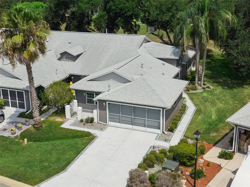 An aerial view shows a gray house with a shingled roof, driveway, and palm trees — 26740 CASH COURT, LEESBURG, FL
