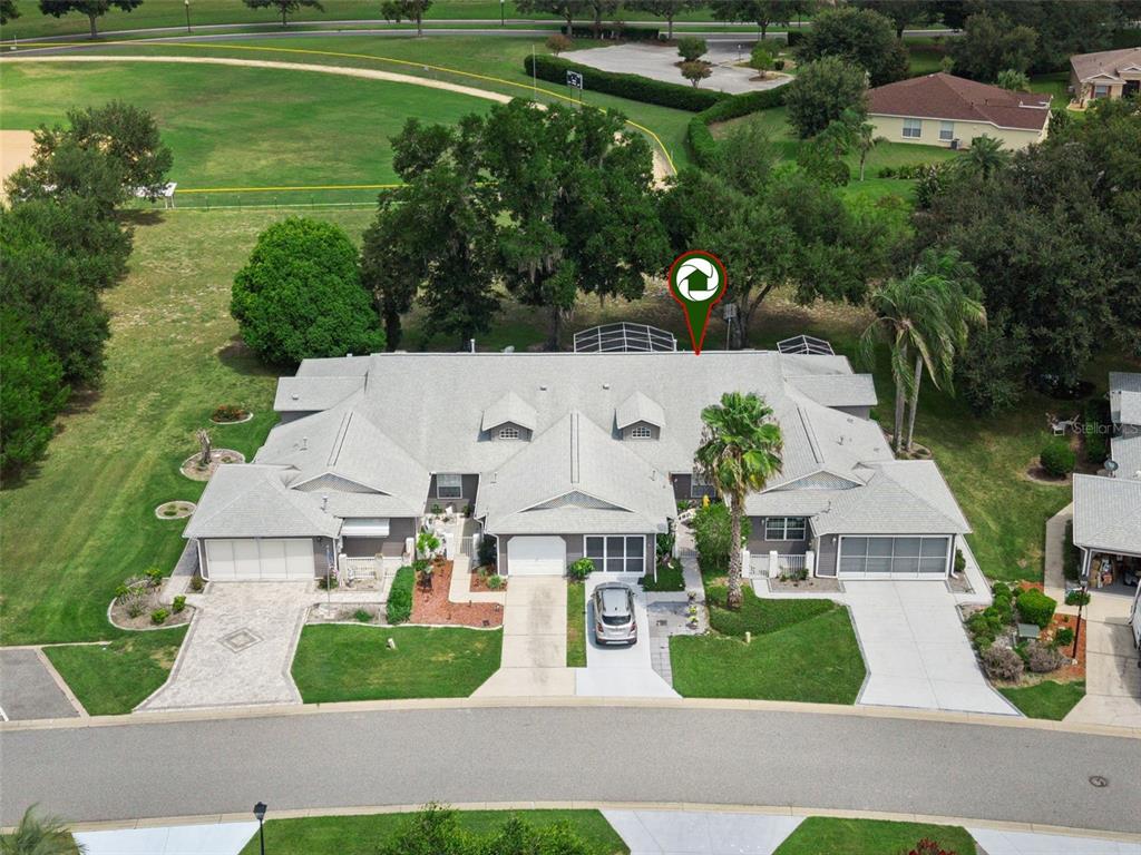 An aerial view shows a multi-unit residential building with gray roofs, garages, and surrounding lawns — 26740 CASH COURT, LEESBURG, FL