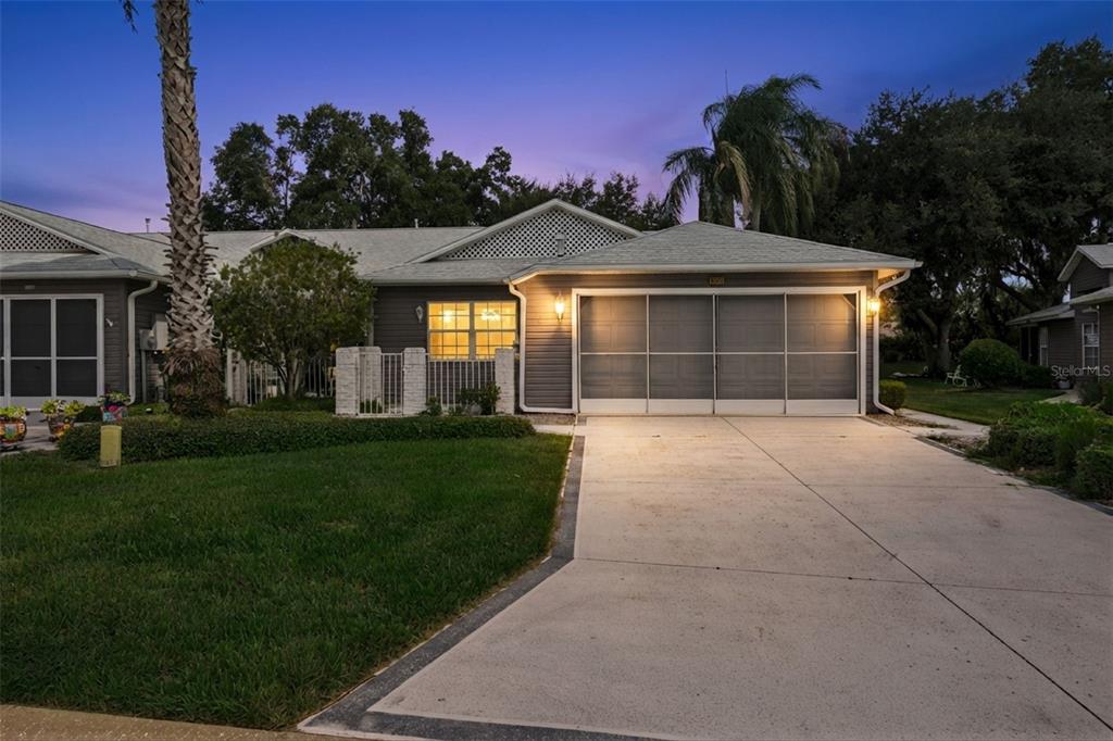 A gray single-story house features a two-car garage, a paved driveway, and a small lawn — 26740 CASH COURT, LEESBURG, FL