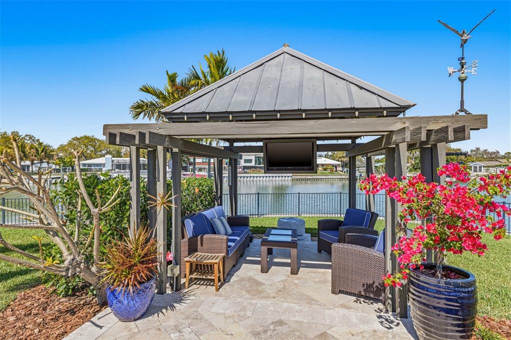 An outdoor gazebo with a metal roof, television, and patio furniture overlooks a waterfront canal — 4310 40TH STREET S, ST PETERSBURG, FL