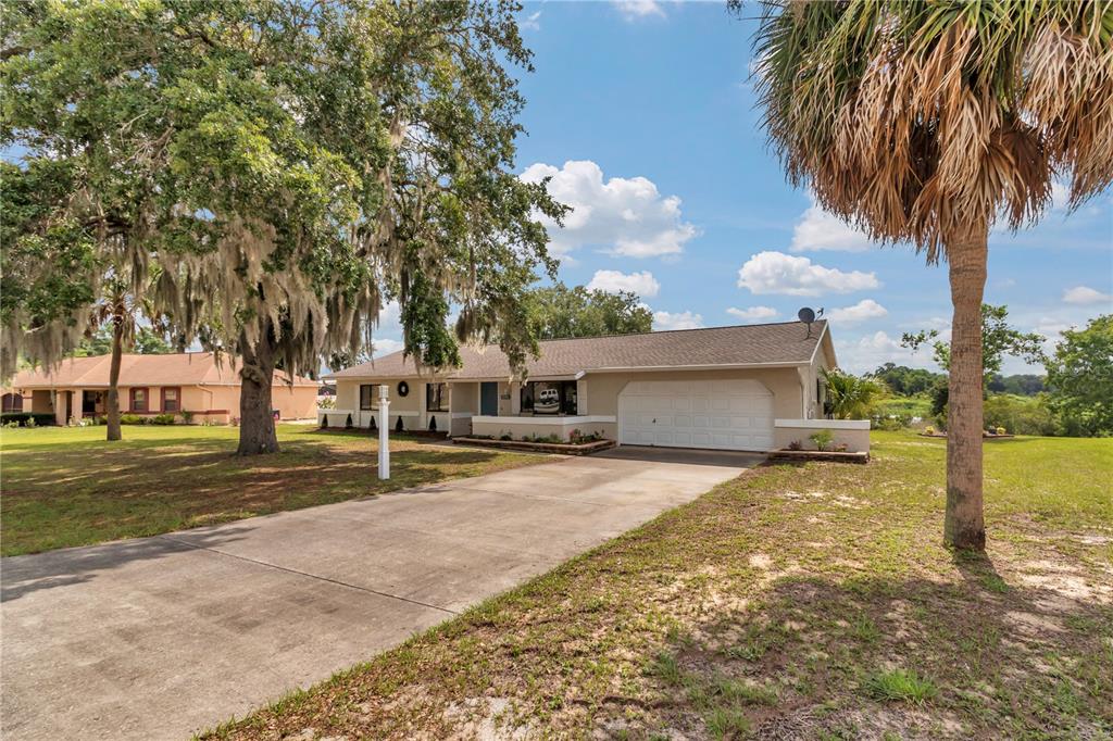 A single-story house with a concrete driveway, a two-car garage, and a large oak tree — 1111 HICKORY ROAD, OCALA, FL