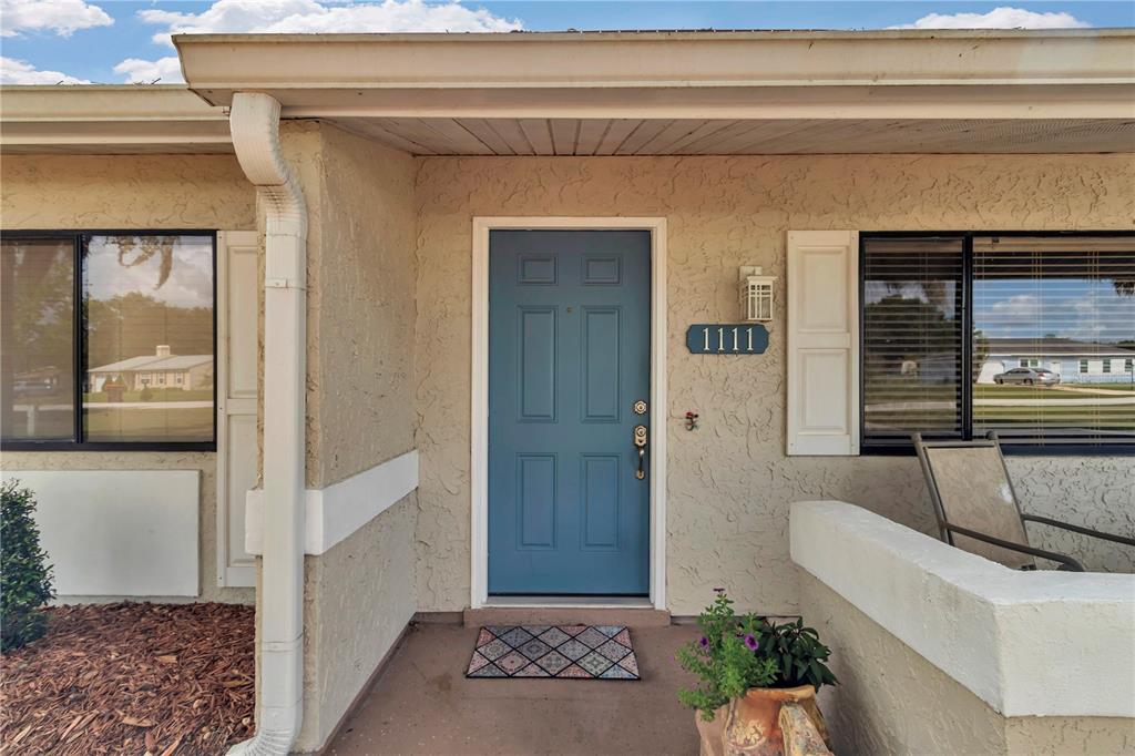 A blue front door with a house number plaque sits under a covered entryway — 1111 HICKORY ROAD, OCALA, FL
