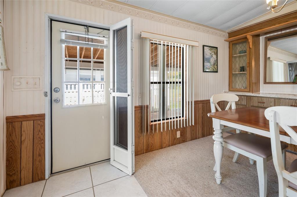 A dining area features wood wainscoting, a white door with a screen, and a window — 6162 REDWING AVENUE, ENGLEWOOD, FL