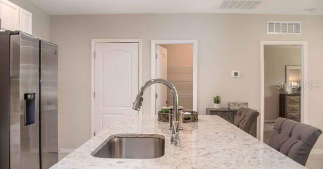 A kitchen island with a stainless steel sink and granite countertop faces a pantry and hallway — 11902 VAN LOON AVENUE, PORT CHARLOTTE, FL