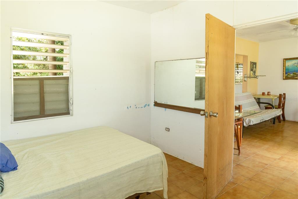 A bedroom with a bed, a wall mirror, and a doorway leading to another room — 16 CALLE SCORPIO, VIEQUES, PR