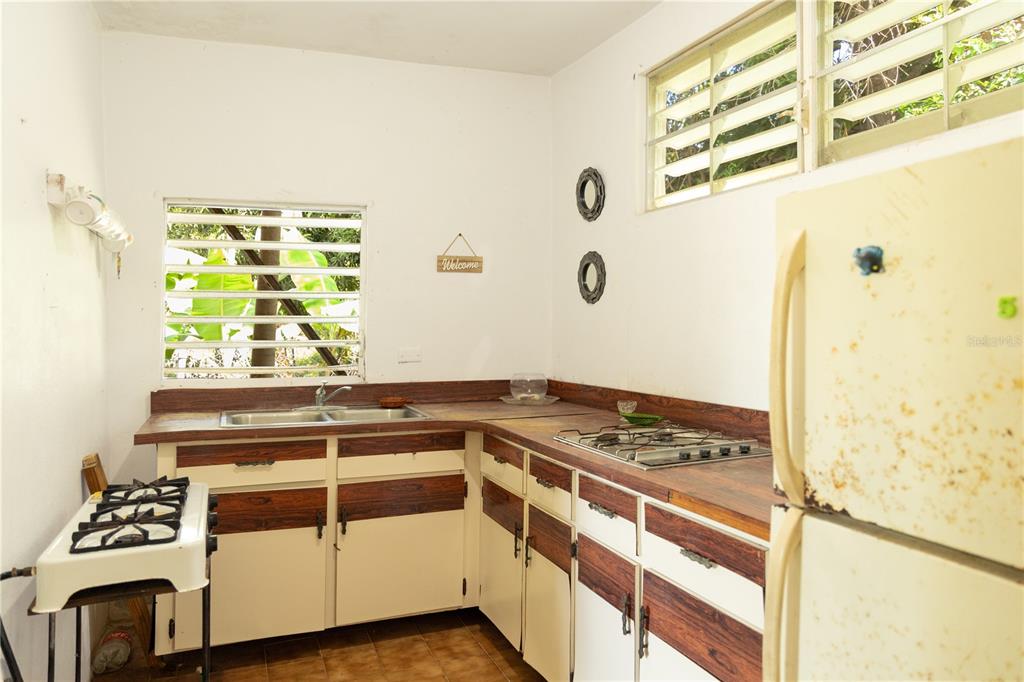 A kitchen features wood-trimmed white cabinets, a double sink, a gas cooktop, and a refrigerator — 16 CALLE SCORPIO, VIEQUES, PR