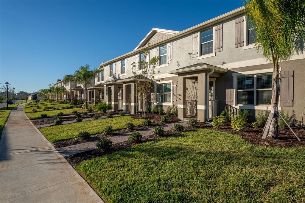 A row of two-story townhomes with beige stucco exteriors, shuttered windows, and small front porches — 13453 SAGESTONE DRIVE, WINTER GARDEN, FL