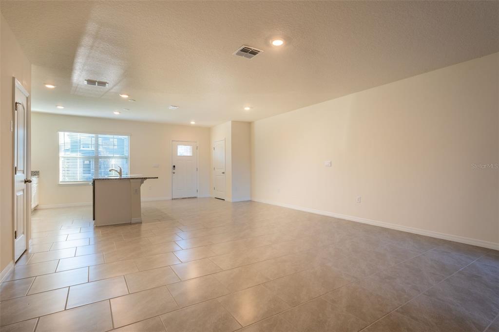 An open-concept living area features light-colored tile flooring, recessed lighting, and a kitchen island — 13453 SAGESTONE DRIVE, WINTER GARDEN, FL