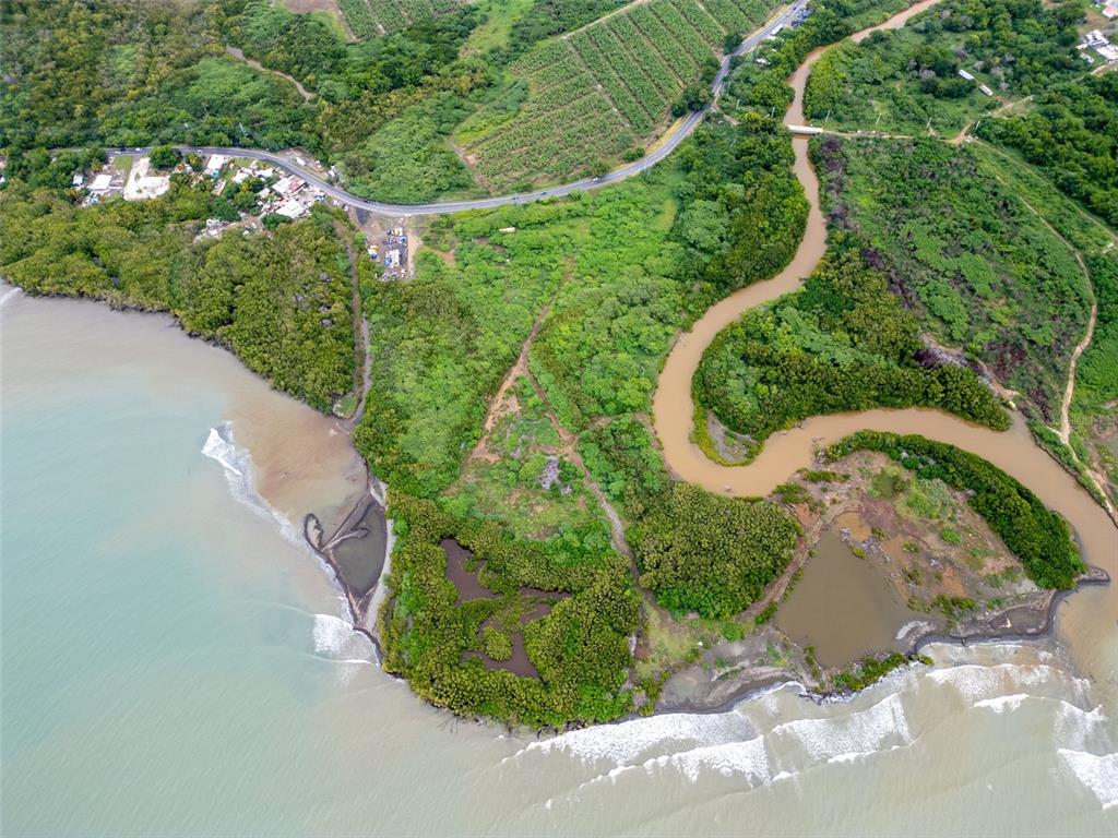 An aerial view shows a winding river meeting the ocean near a coastal road — PR-1 PUEBLO WARD, SALINAS, PR