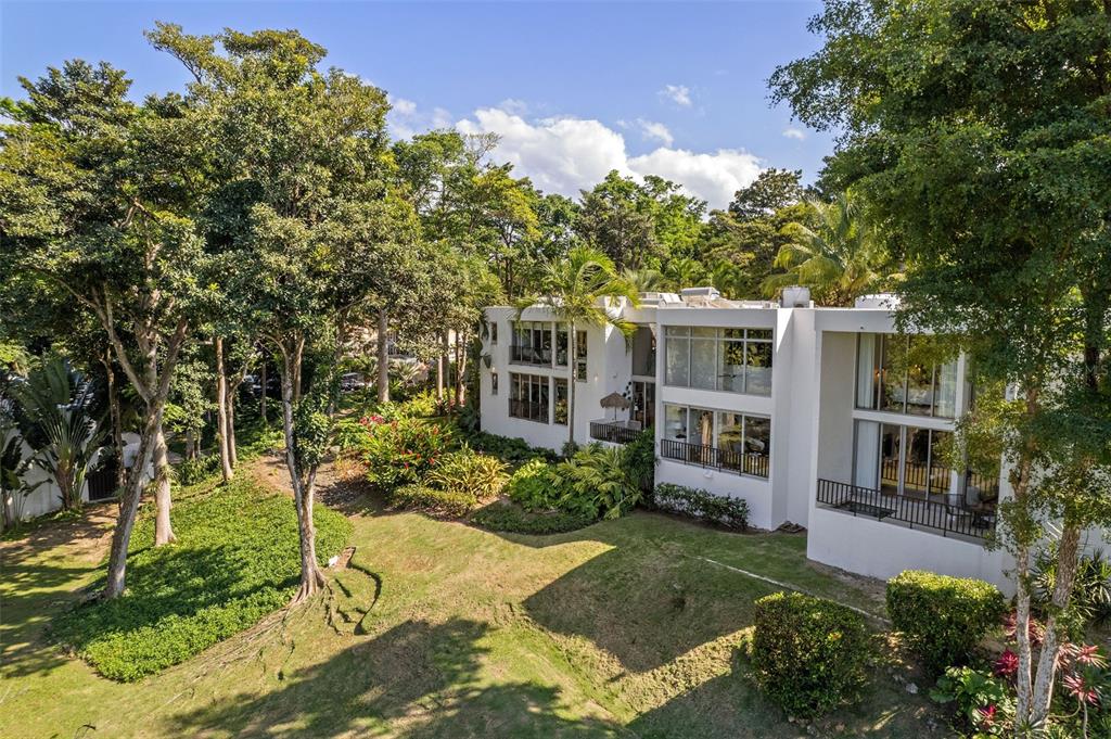 A modern white multi-story house sits on a grassy hill surrounded by lush green trees — 2613 VILLAS DORADO ESTATES, DORADO, PR