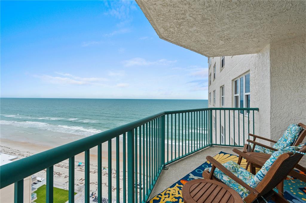 A balcony with green railings overlooks the ocean and sandy beach from a high-rise building — 2055 S ATLANTIC AVENUE UNIT 1402, DAYTONA BEACH, FL