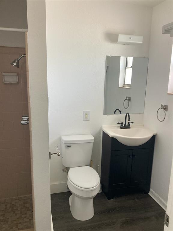 A bathroom with a shower, a white toilet, and a dark vanity with a sink — 1401 E ALFRED STREET UNIT 11, TAVARES, FL