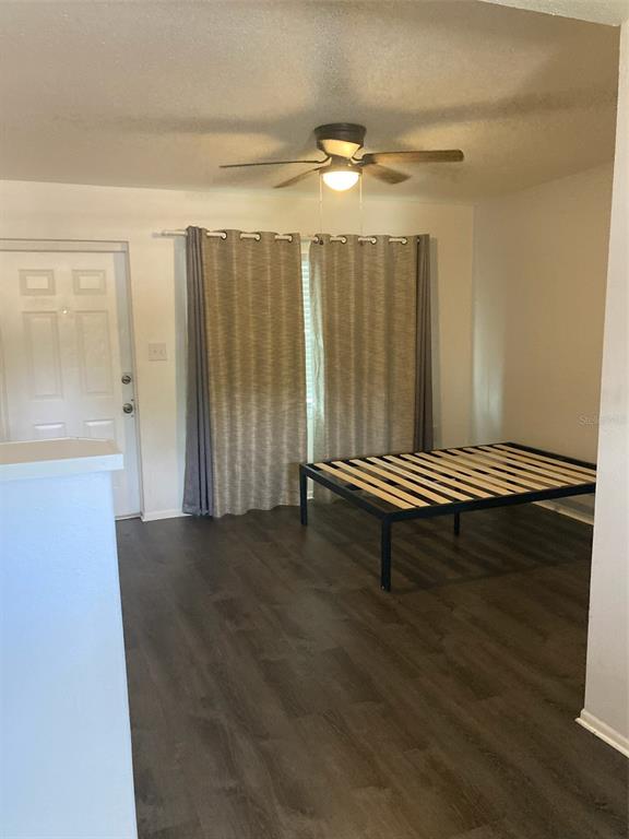 A bedroom features dark wood-look flooring, a ceiling fan, and a metal bed frame — 1401 E ALFRED STREET UNIT 11, TAVARES, FL