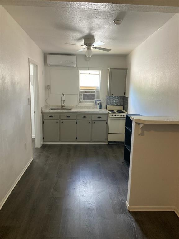 A kitchen features gray cabinets, a white stove, a ceiling fan, and dark wood flooring — 1401 E ALFRED STREET UNIT 11, TAVARES, FL