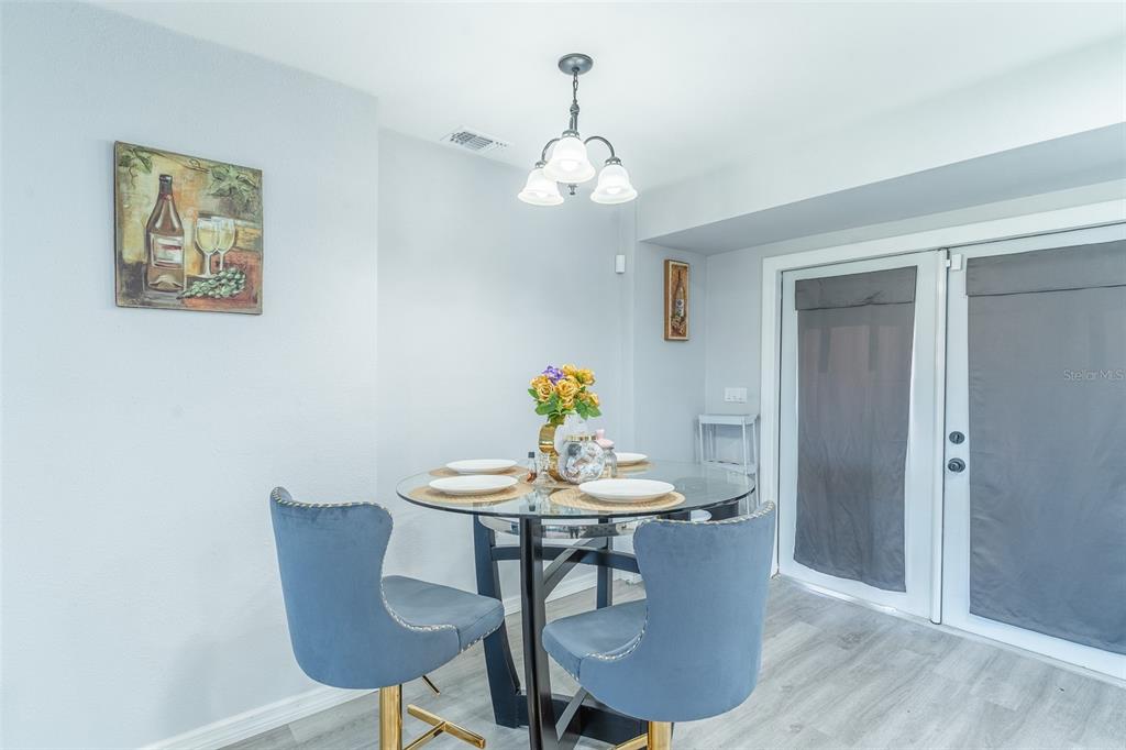 A dining area features a glass-topped table, blue velvet chairs, and light wood flooring — 713 GREENLEAF LANE, LAKE WALES, FL