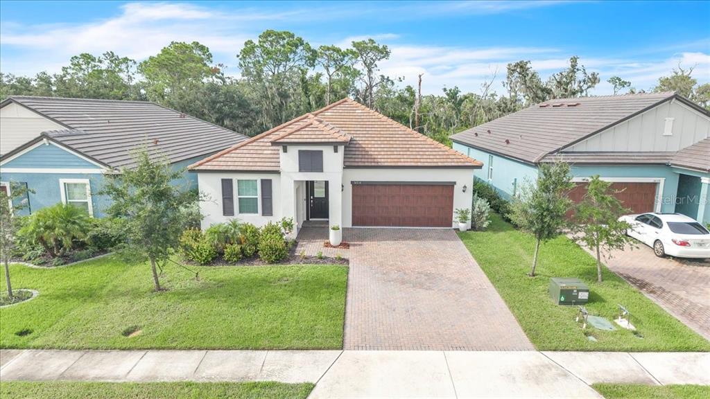 A single-story house with a tiled roof, brick driveway, and attached garage sits between neighbors — 14314 17TH COURT E, PARRISH, FL