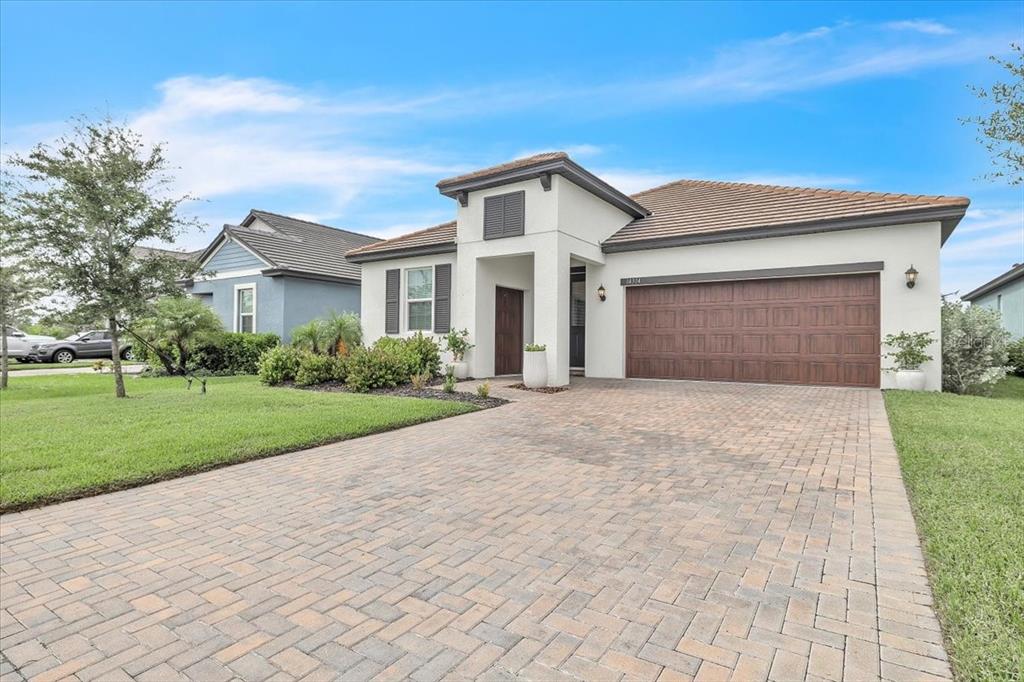 A single-story house with a paved driveway, a two-car garage, and a white stucco exterior — 14314 17TH COURT E, PARRISH, FL