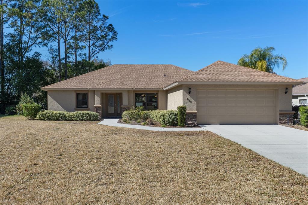 A single-story house with a tan stucco exterior, a two-car garage, and a brown roof — 2388 N BRENTWOOD CIRCLE, LECANTO, FL