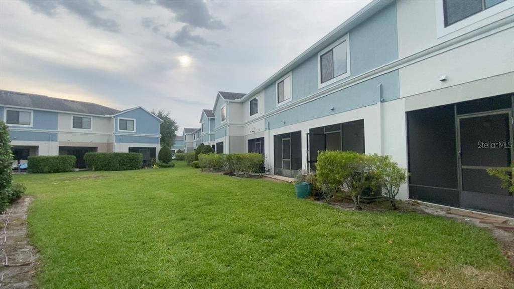 The exterior of a multi-unit residential building features a grassy lawn and screened-in patios — 1131 TRILLIUM PARK LANE, SANFORD, FL