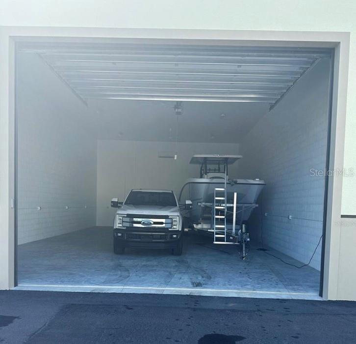 A large, empty garage contains a white pickup truck and a boat on a trailer — 25155 AIRPORT ROAD UNIT A-1, PUNTA GORDA, FL