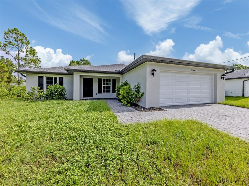 A single-story house with a white stucco exterior, a two-car garage, and a paved walkway — 22444 DONALDA AVENUE, PORT CHARLOTTE, FL