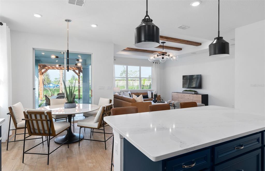 A kitchen island overlooks an open-concept living and dining area with modern light fixtures — 2641 FERMOY DRIVE, ORMOND BEACH, FL
