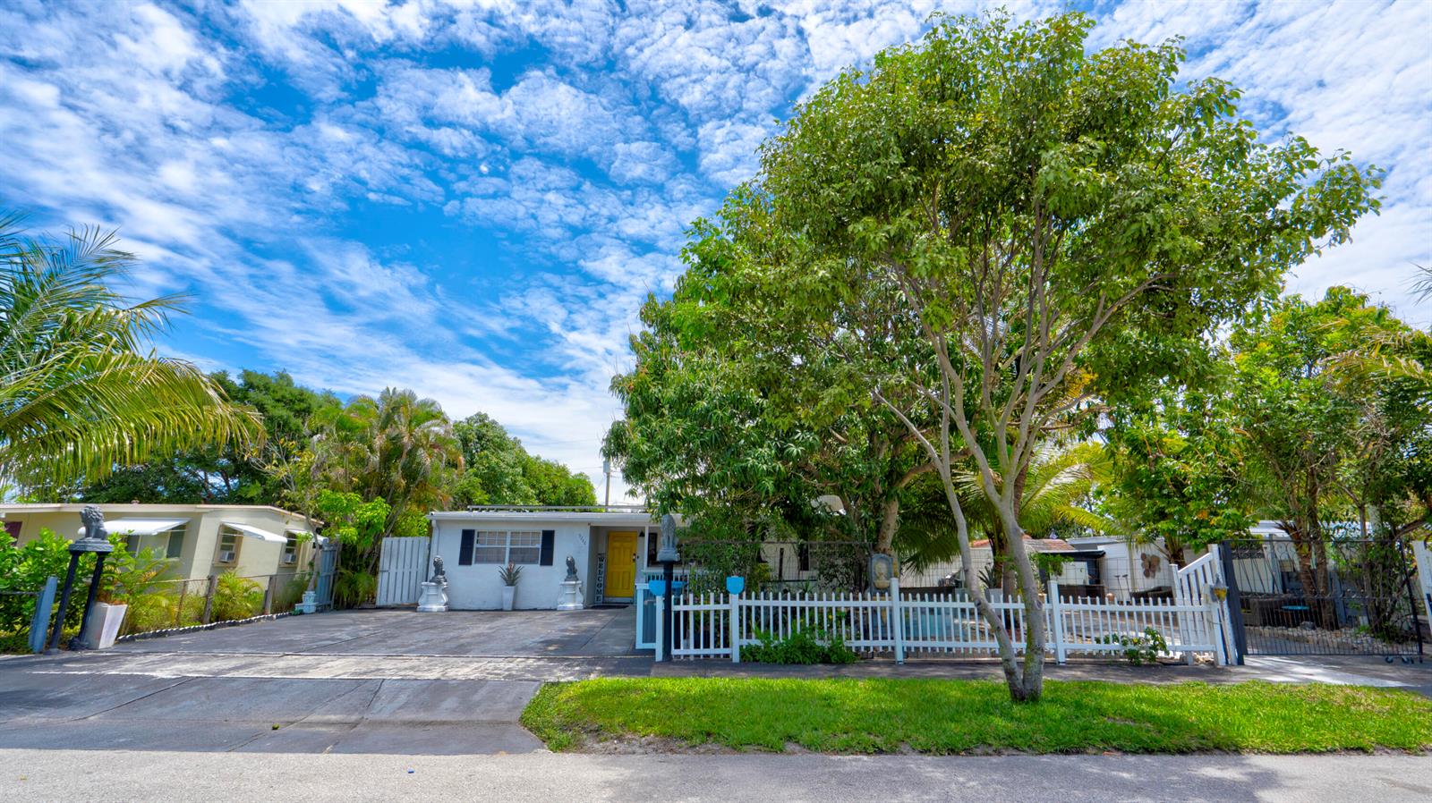 A white single-story house with a yellow door is behind a white picket fence — 3246 Orange Street, Boynton Beach FL 33435, BOYNTON BEACH, FL