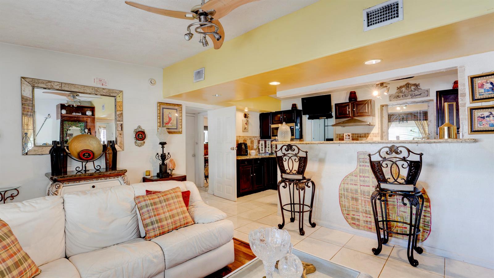 A living room with a white sofa, bar stools, and an open kitchen area — 3246 Orange Street, Boynton Beach FL 33435, BOYNTON BEACH, FL