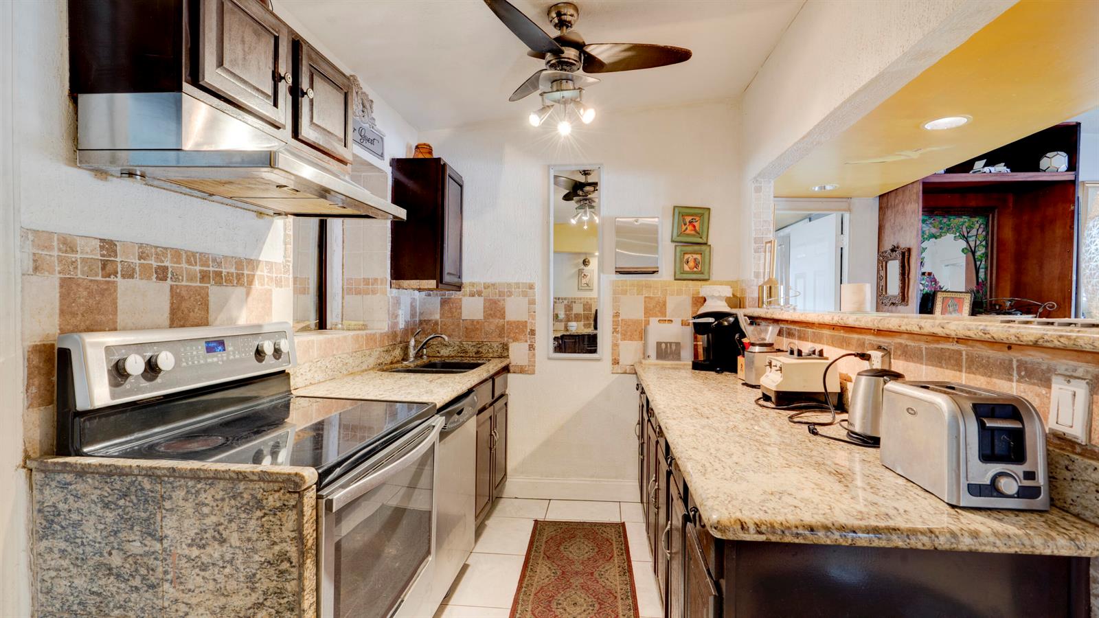 A kitchen features granite countertops, dark wood cabinets, stainless steel appliances, and a tiled backsplash — 3246 Orange Street, Boynton Beach FL 33435, BOYNTON BEACH, FL