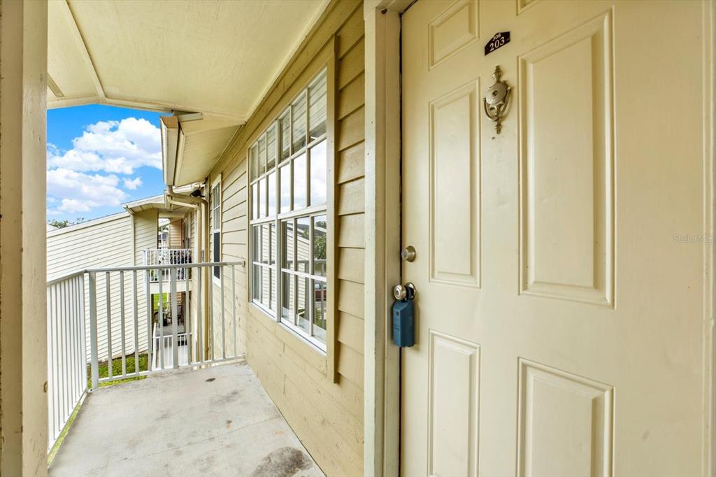 An exterior view of an apartment balcony with a beige door and a lockbox — 308 LAKE PARSONS GREEN UNIT 203, BRANDON, FL