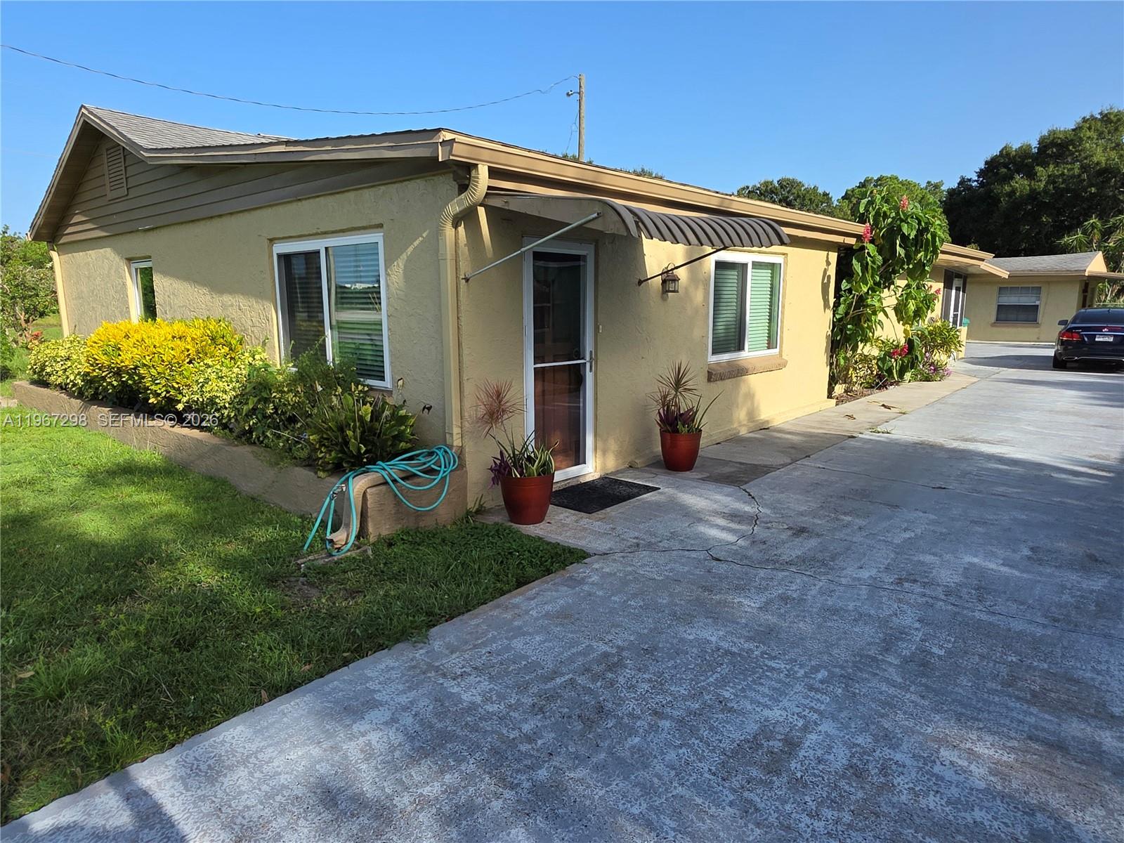A single-story yellow stucco building features a concrete driveway, a small awning, and landscaping — 4321 Kirby Loop Rd # 1, Fort Pierce FL 34981, FORT PIERCE, FL