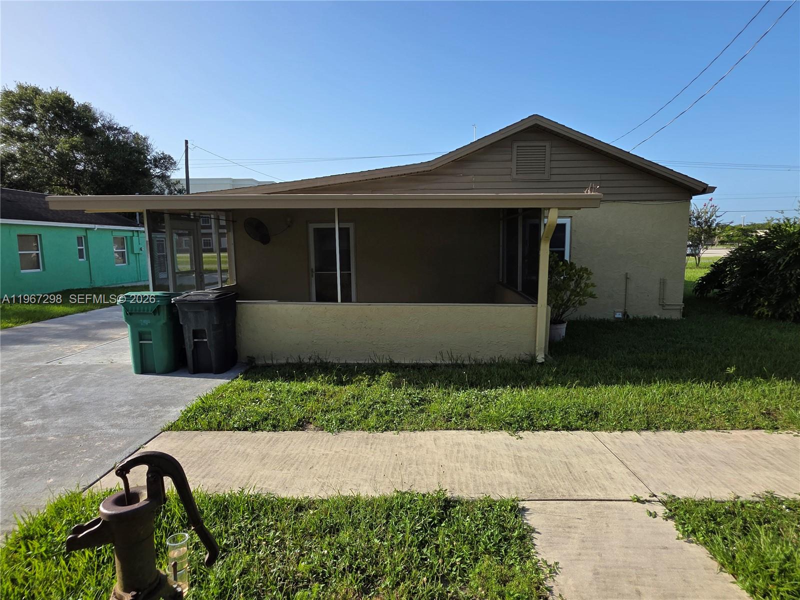 A tan house features a screened-in porch, a concrete driveway, and a front yard — 4321 Kirby Loop Rd # 1, Fort Pierce FL 34981, FORT PIERCE, FL